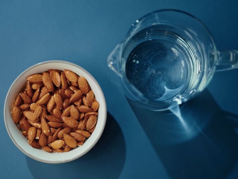 prikaz badema u činiji i bokala sa vodom.