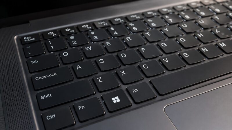 Moderan poslovni laptop na radnom stolu sa jasno prikazanom tastaturom, velikim tačpedom i elegantnim kućištem.